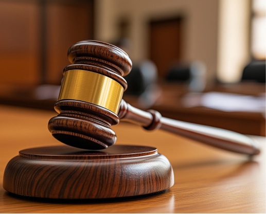 Esecuzioni Mobiliari e Immobiliari. Un martelletto da giudice posato su un tavolo di legno, simbolo della giustizia e del sistema legale in un aula di tribunale.